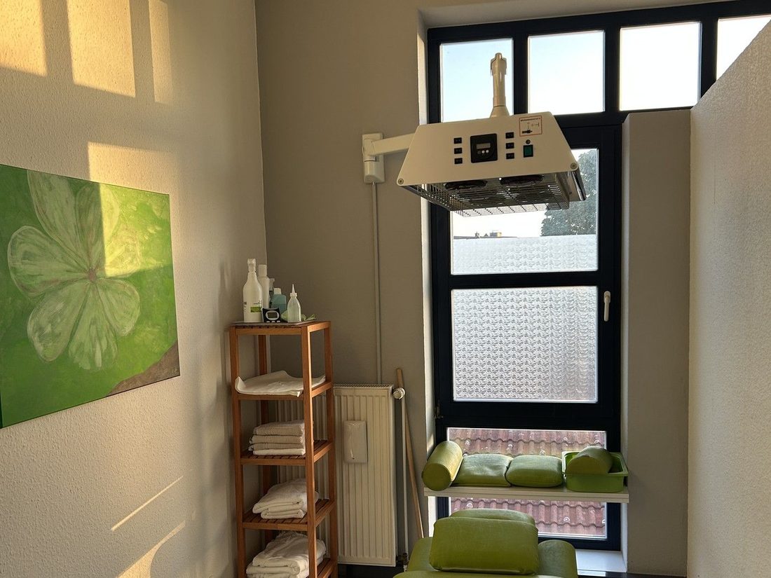 Behandlungsraum mit Therapieliege, Wärmestrahler und großem Fenster